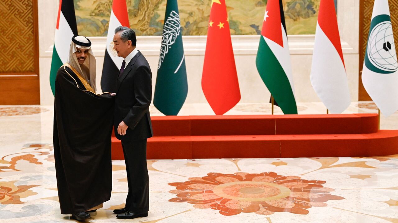 China's foreign minister, Wang Yi (R), shakes hands with Saudi Arabia's foreign minister, Prince Faisal bin Farhan Al-Saud, before a family photo for the attendees of a meeting of foreign ministers from Arab and Muslim-majority nations at the Diaoyutai State Guest House in Beijing on November 20, 2023. 